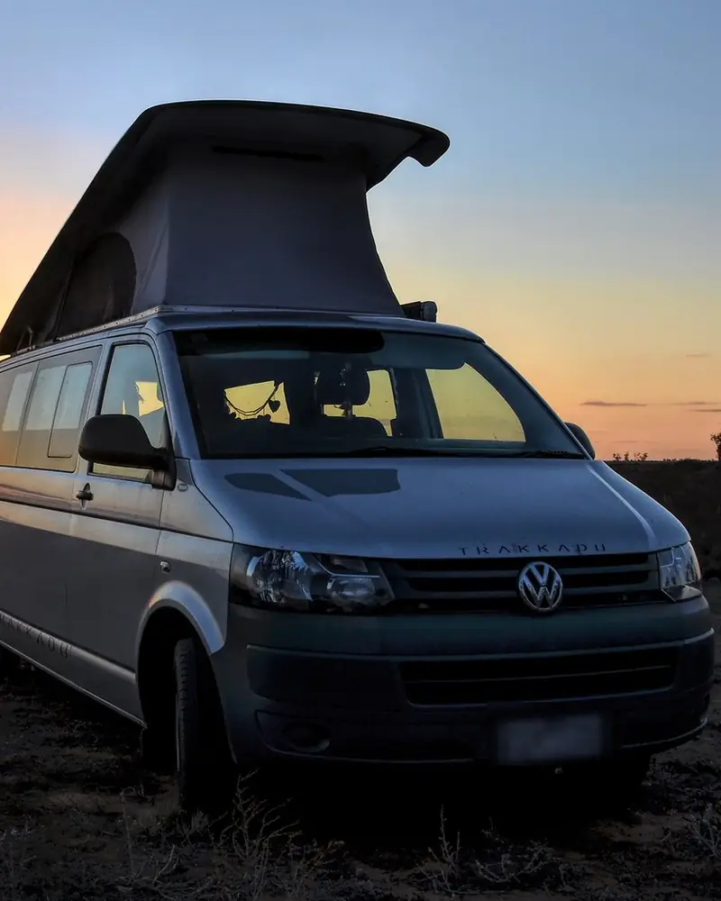 Furgoneta camper con el techo elevable, a contraluz mientras se pone el sol